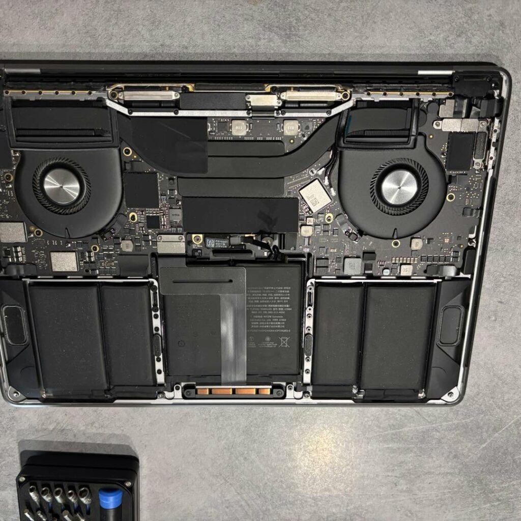 MacBook Pro ouvert à l'atelier : ventilateurs, batterie et carte mère visibles